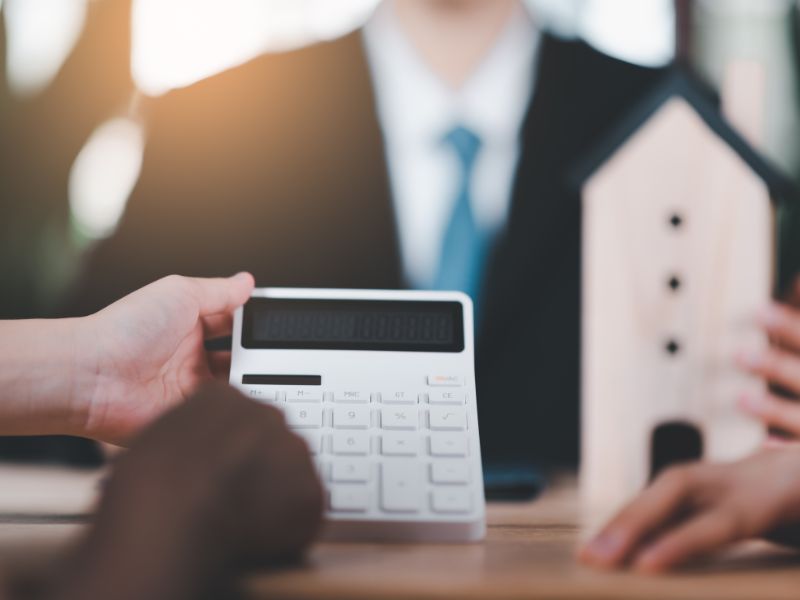 uomo con calcolatrice e modellino di palazzo