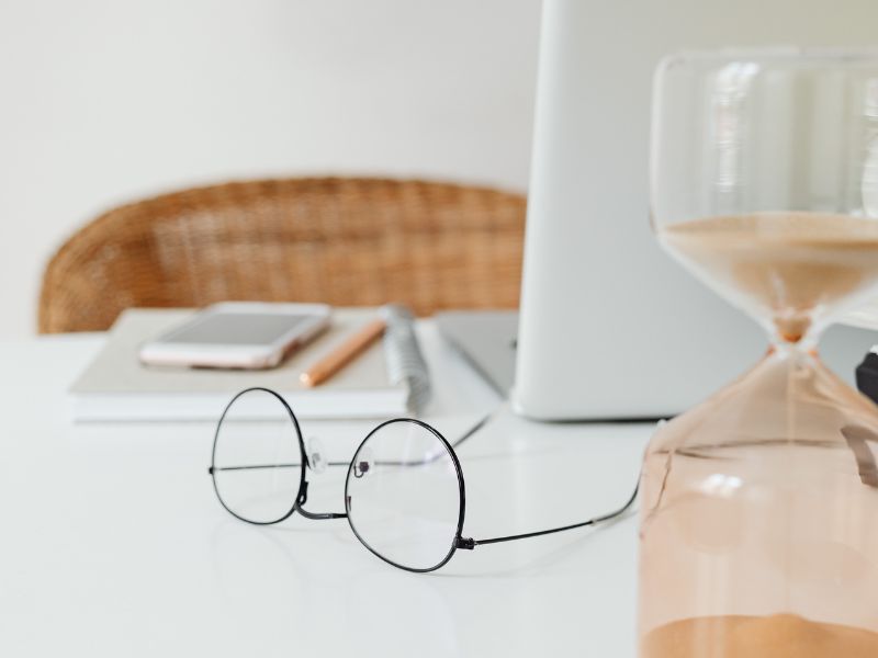 clessidra su un tavolo con occhiali e computer