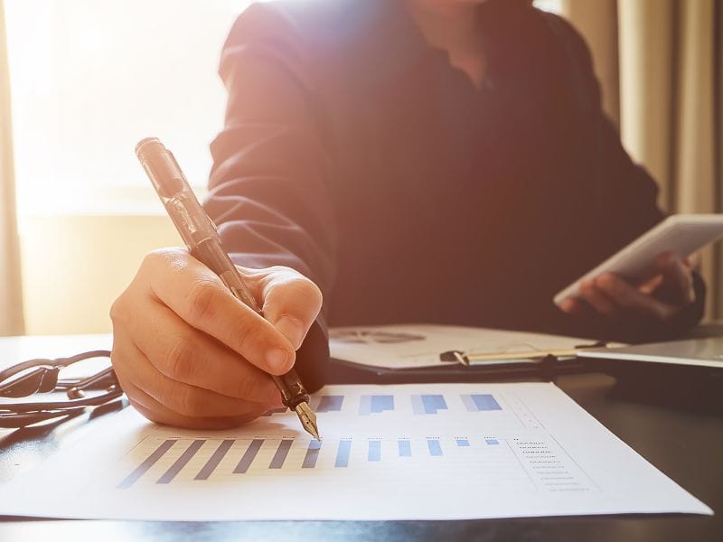 donna fa conti con penna sulla scrivania in ufficio