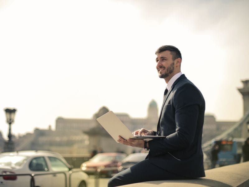 uomo con computer in città guarda gli investimenti immobiliari
