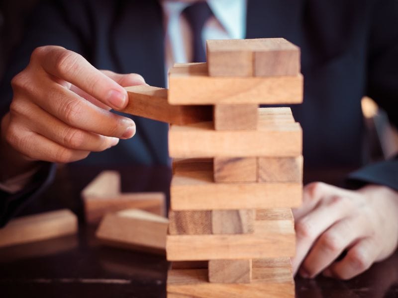 uomo toglie un tassello di legno da una costruzione