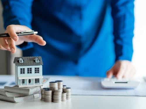 uomo con modellino di casa e denaro sulla scrivania
