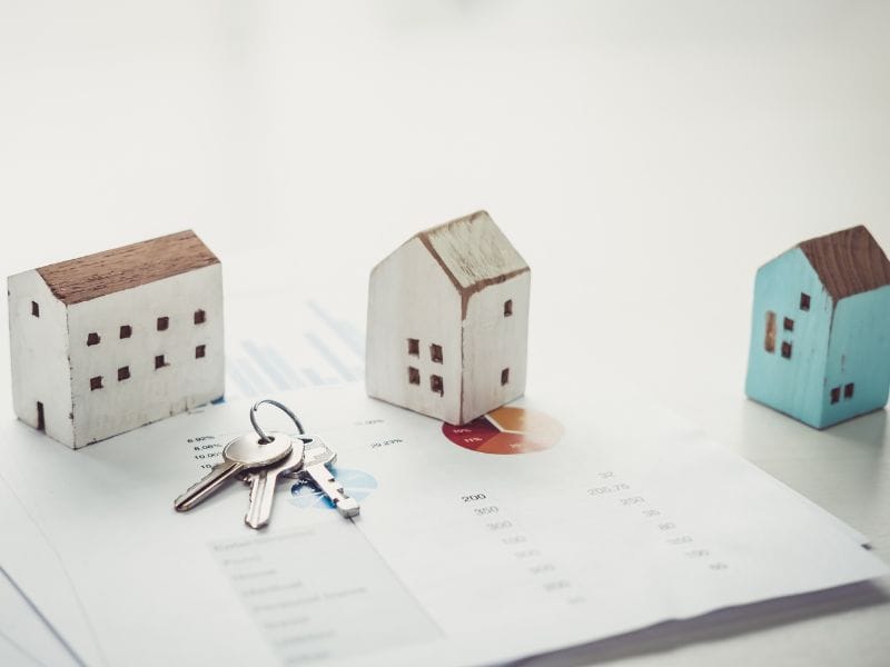 tre modellini di casa con chiave sopra un business plan di investimento immobiliare residenziale