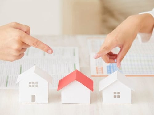 due mani indicano modellini di case