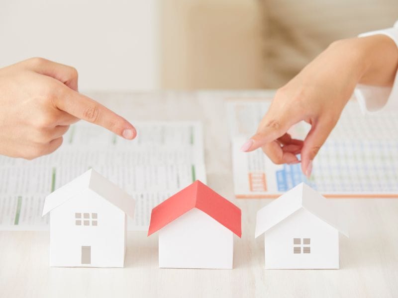 due mani indicano modellini di case